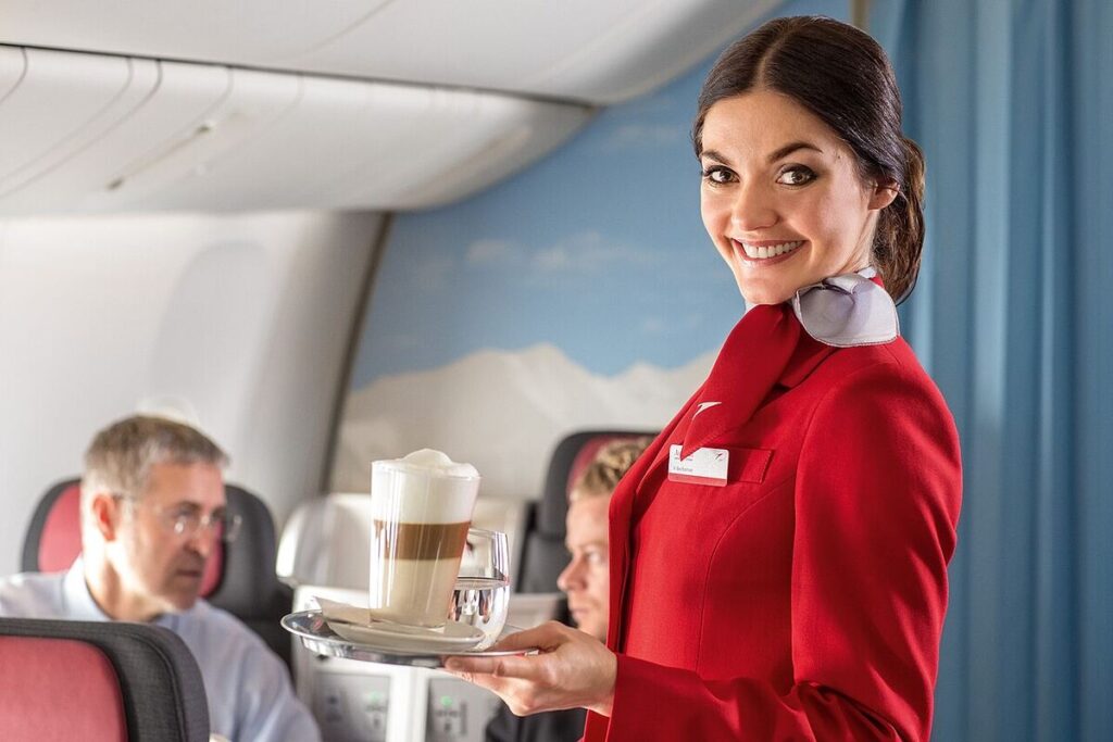 An Austrian Airlines flight attendant serving refreshments to passengers