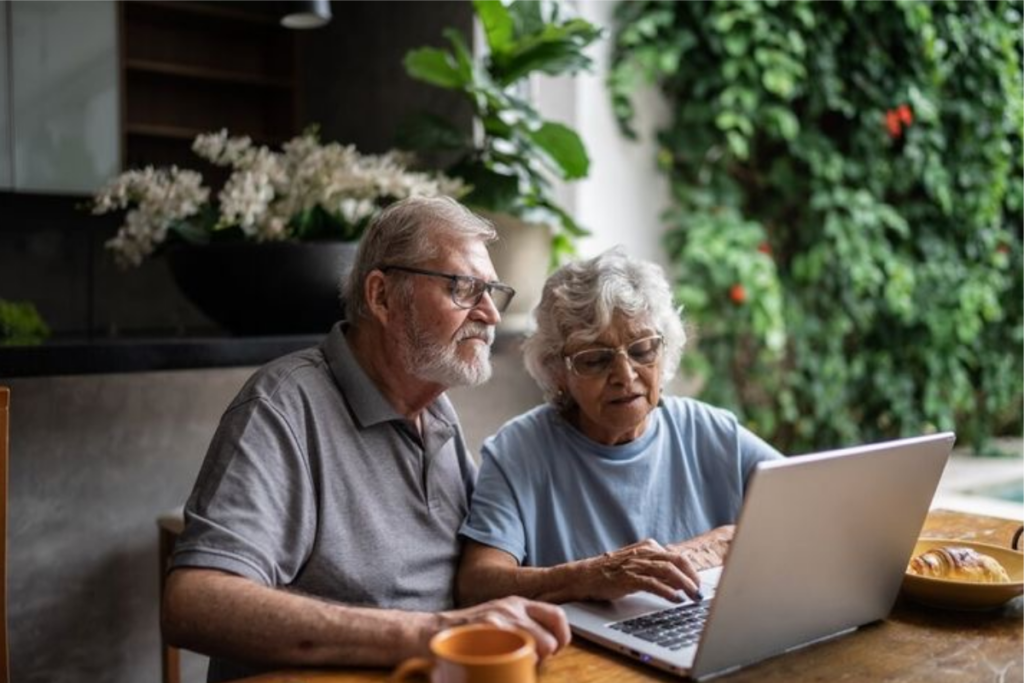 An image of an elderly couple typing on a laptop