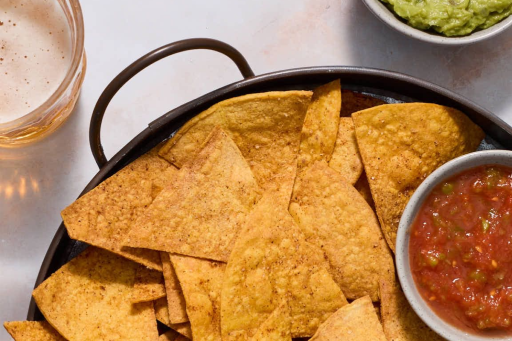 An image of tortilla chips on a dish with dips