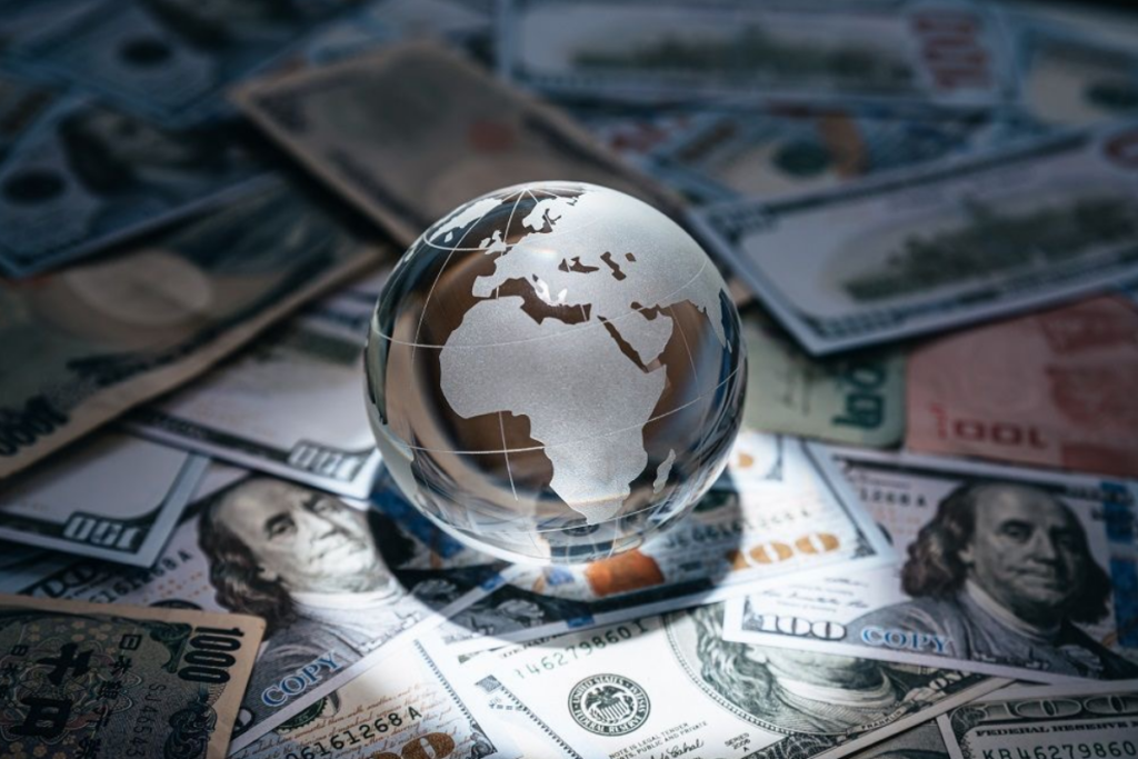 An image of a globe at center with a table filled with money