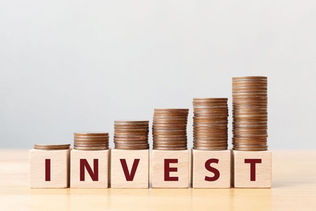 An image of coins stacked on blocks with the word “invest”