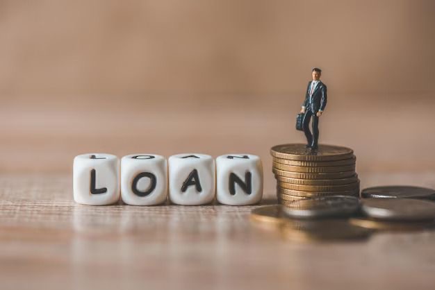 An image showing stacked coins with the word “loan” spelled out on Blocks