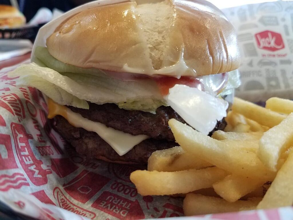 A bacon ultimate cheeseburger with lettuce and onions made in La Jolla