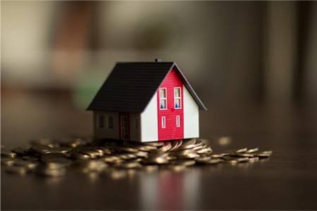 A model house sitting on a mound of coins