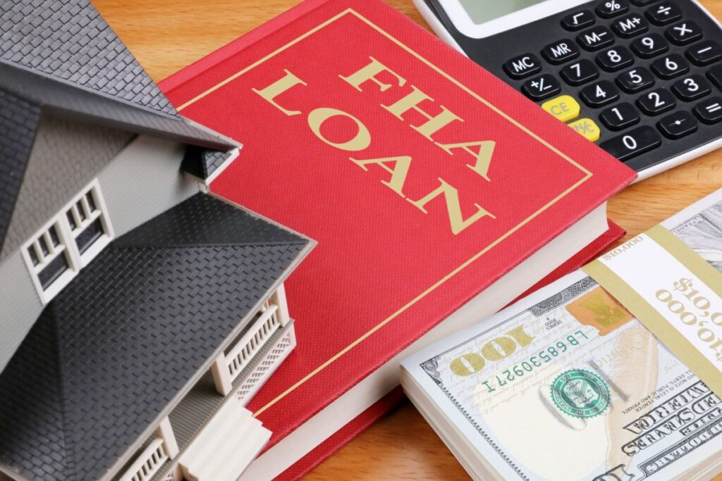 Model house atop a hard-bound book and a wad of cash