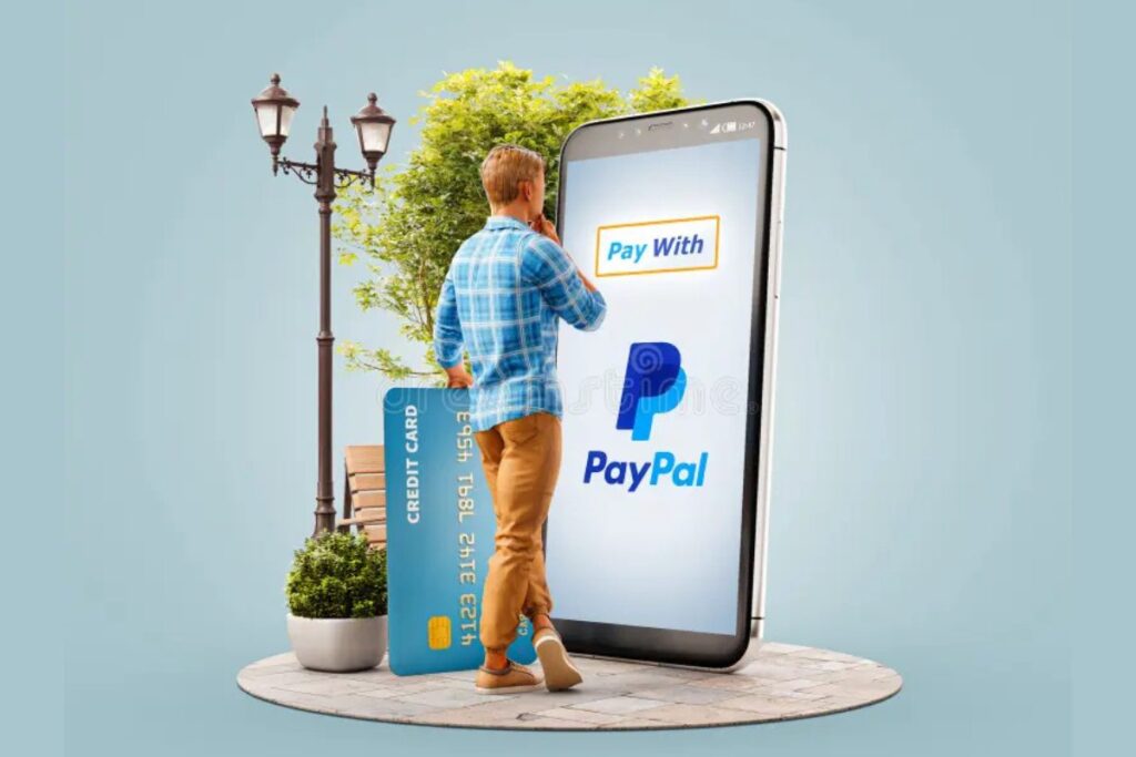 An image of a man standing by a large sized phone with "PayPal App" in it