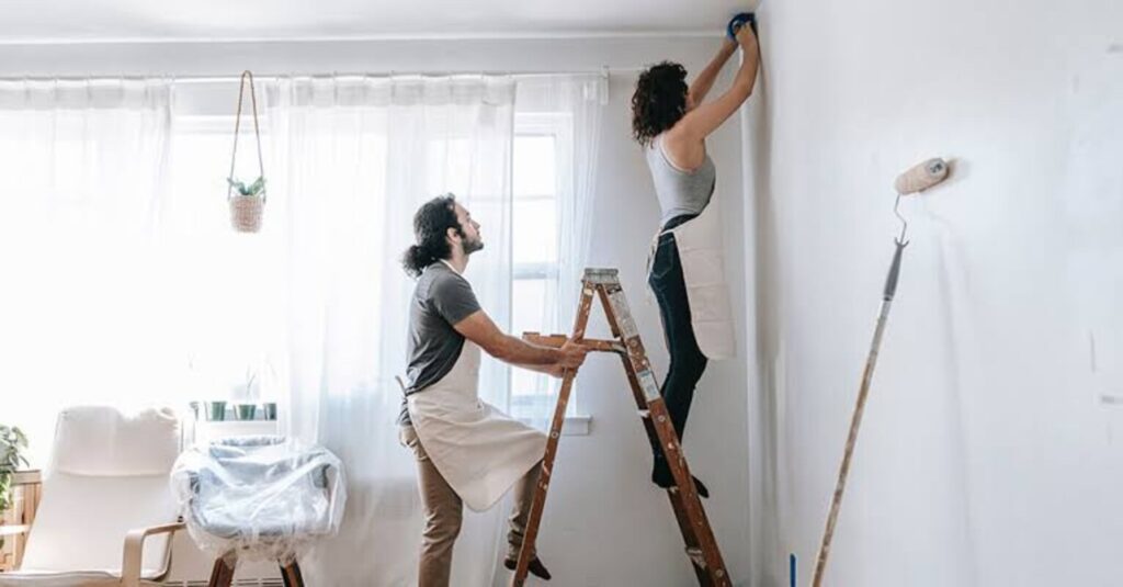 A man holding a ladder for his wife