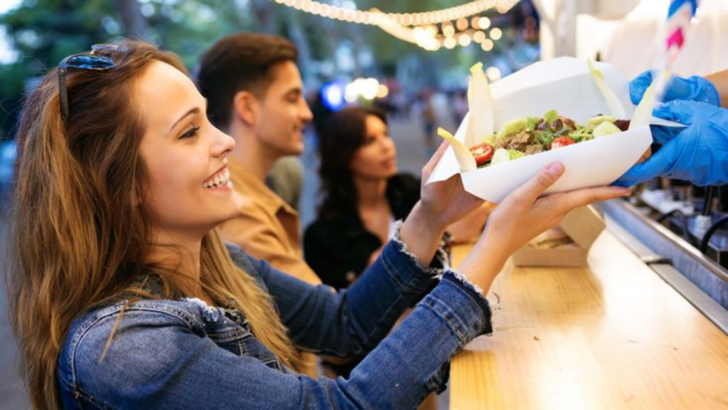 A customer receiving a food package from a food truck