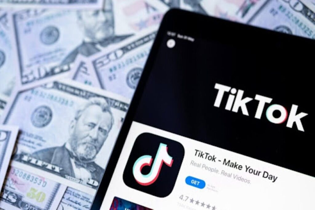 The TikTok official account is on a smartphone screen and dollar bills in set