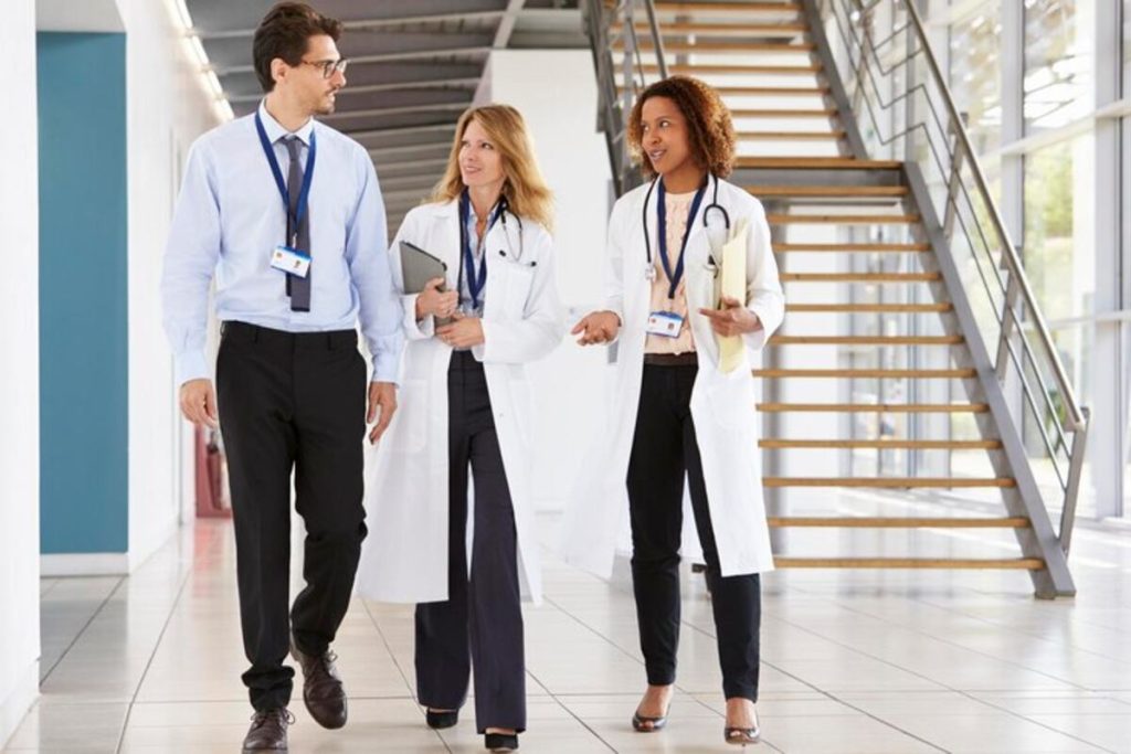 Three young male and female doctors walking in hospital